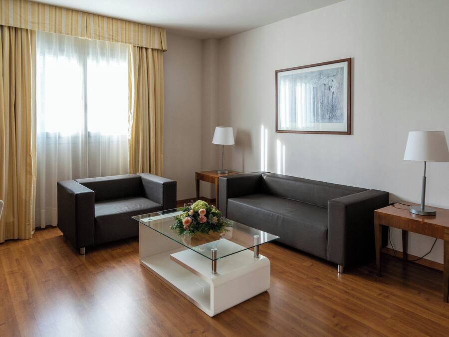 A modern living room with a glass coffee table, two sofas, a side table, and a lamp.