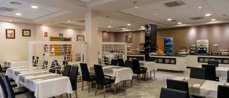 Un restaurante con varias mesas, sillas y una barra con una máquina de café.