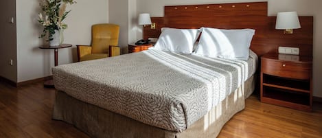 Habitación de hotel impecable con una cama grande, mesitas de noche, una silla y un adorno decorativo en la pared.