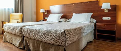 A hotel room with two beds, a wooden headboard, a chair, a nightstand, and a wall with motivational text.