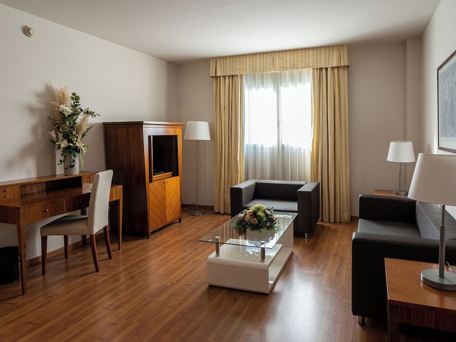 Una habitación de hotel moderna con un escritorio de madera, un sofá, una mesa de centro y una televisión.