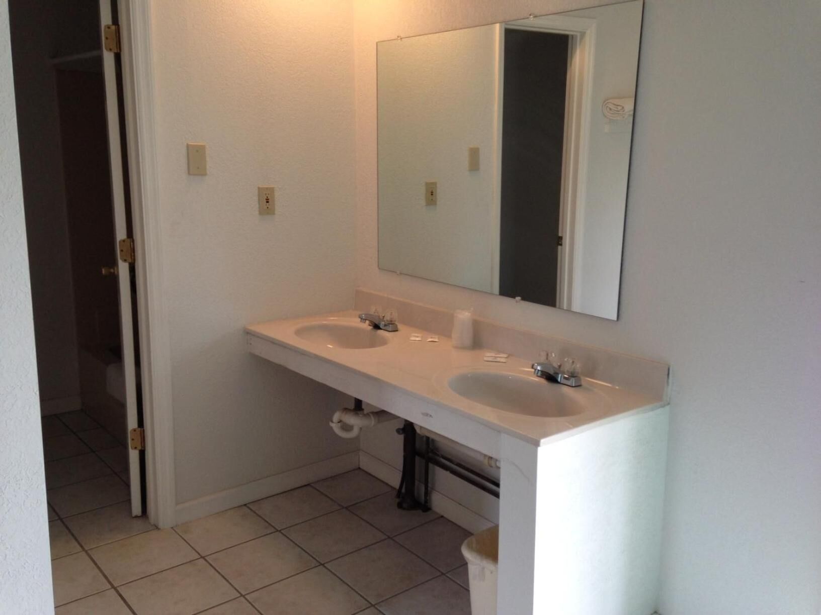 A bathroom with two sinks, a mirror, and a toilet.