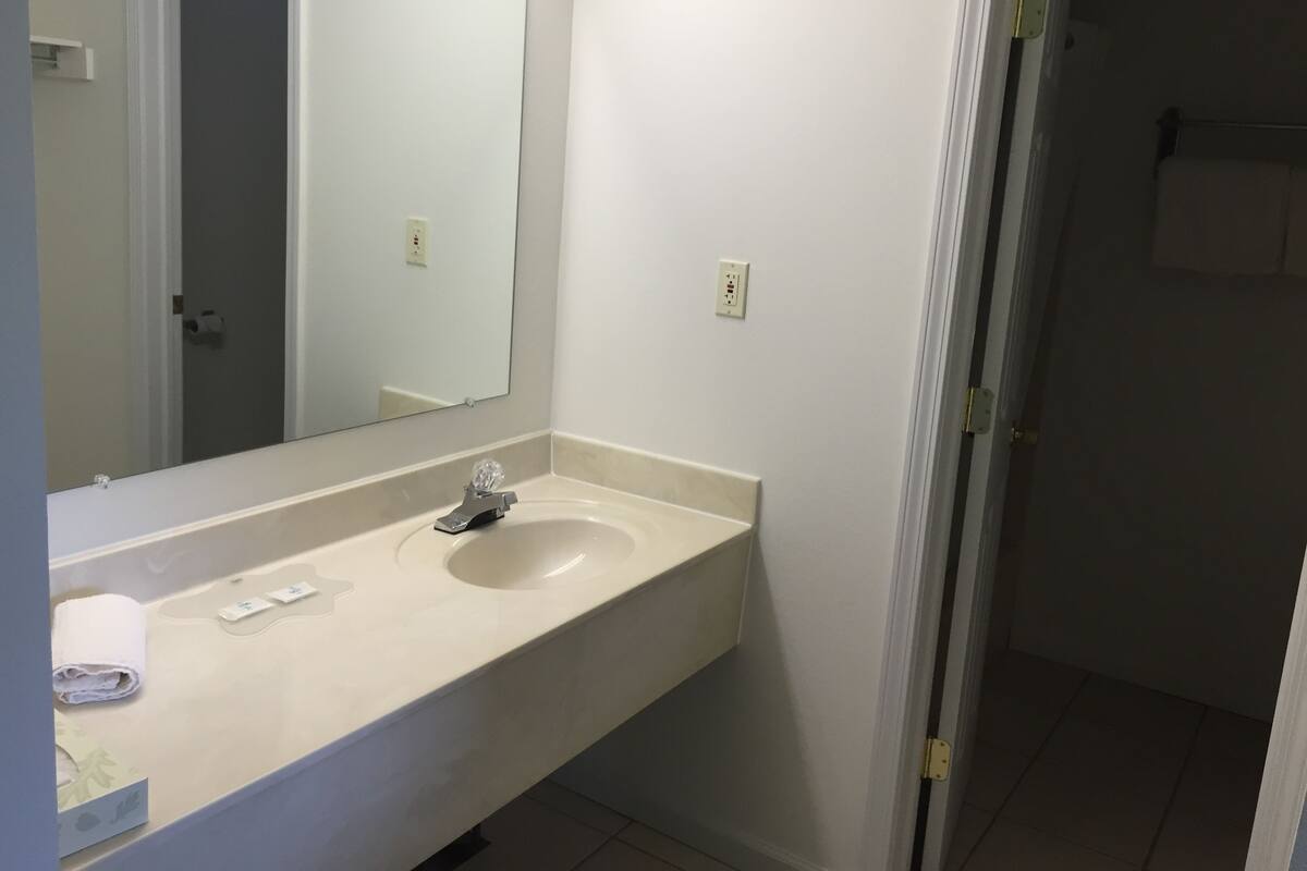 Une salle de bain avec un lavabo blanc, un miroir et un porte-serviettes.