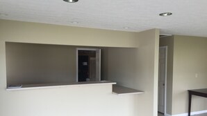 Ein Zimmer mit eingebautem Sitzplatz, einer Tür zu einem weiteren Raum und einem Fliesenboden.