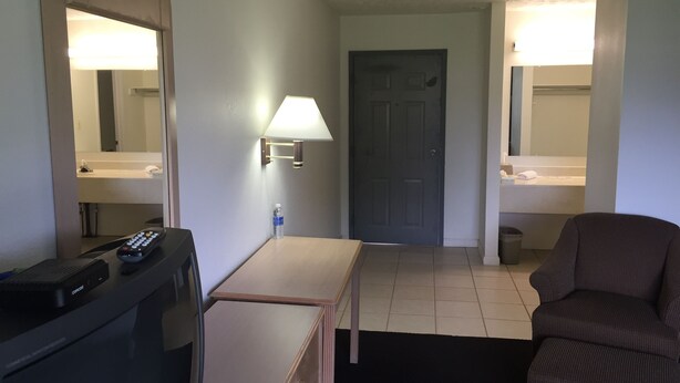 Ein Hotelzimmer mit Schreibtisch, Fernbedienung, Lampe, Tür und Sofa.