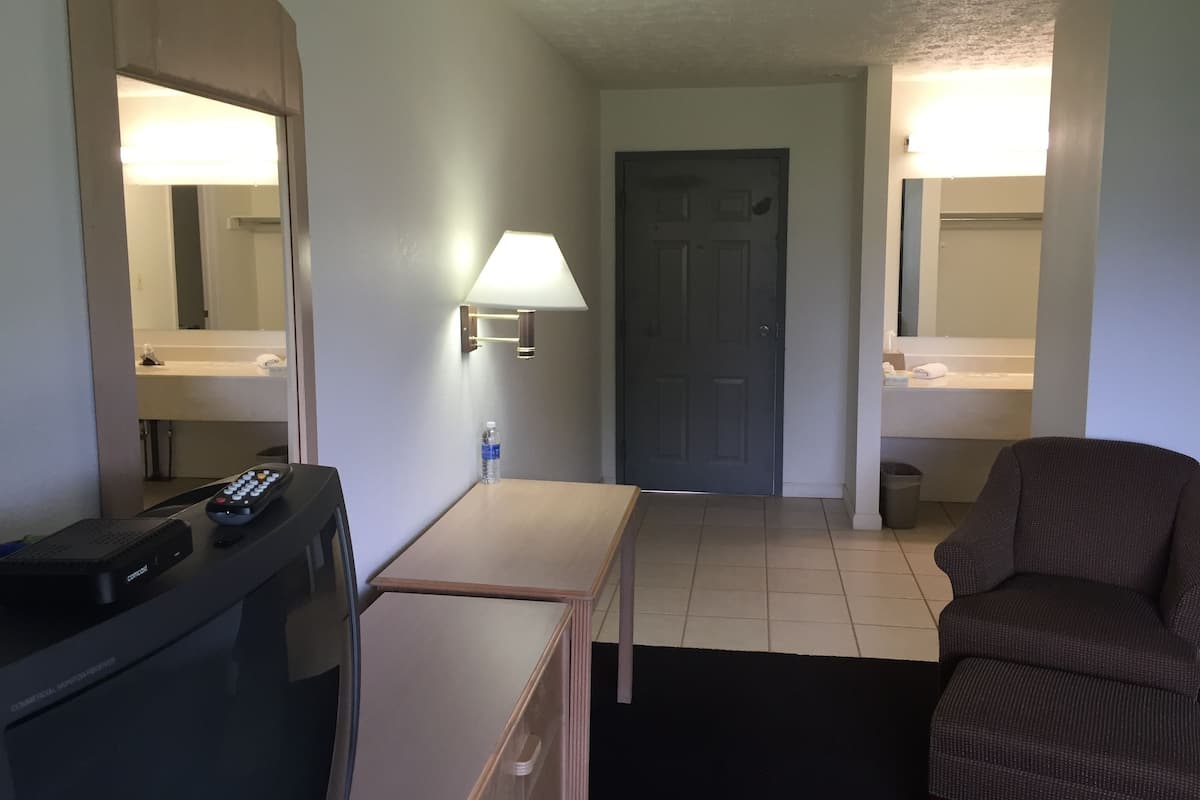 Une chambre d’hôtel équipée d’un bureau, d’une télécommande, d’une lampe, d’une porte et d’un canapé.
