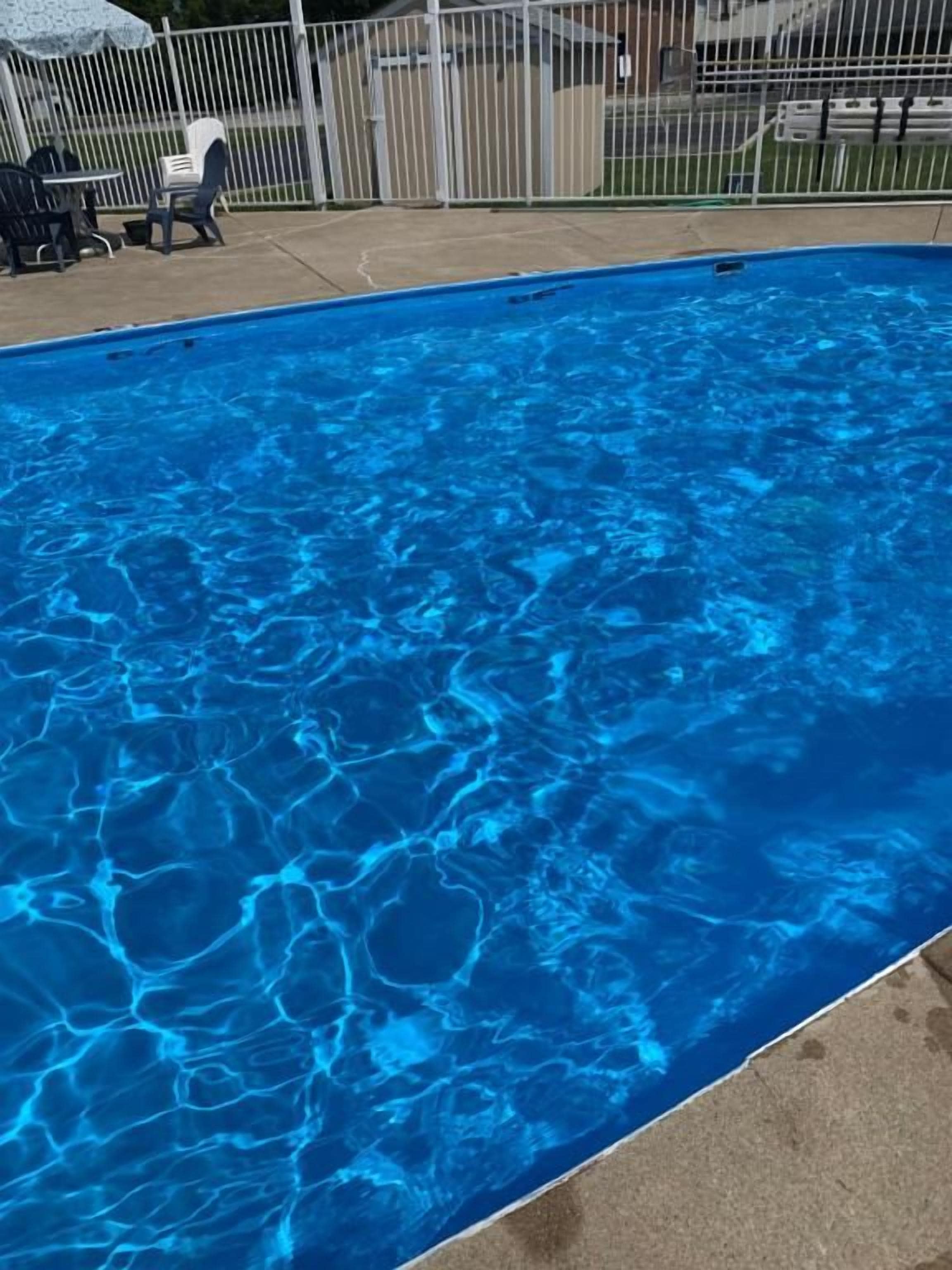 Une piscine à l’eau d’un bleu limpide, entourée d’une clôture.