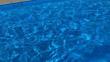 Una piscina con agua cristalina y azul, rodeada por una valla.