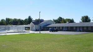 A motel with a swimming pool, a parking lot, and a grassy area.