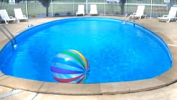 A swimming pool with a colorful beach ball and lounge chairs around the perimeter.