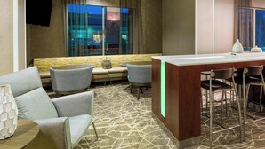 Un vestíbulo de hotel con una zona de estar, un bar y un televisor montado en la pared.