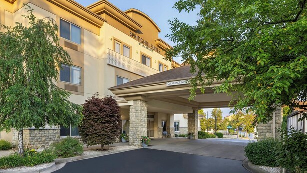 L’entrée d’un hôtel, avec un patio abrité, des piliers en pierre et une allée bien dégagée.
