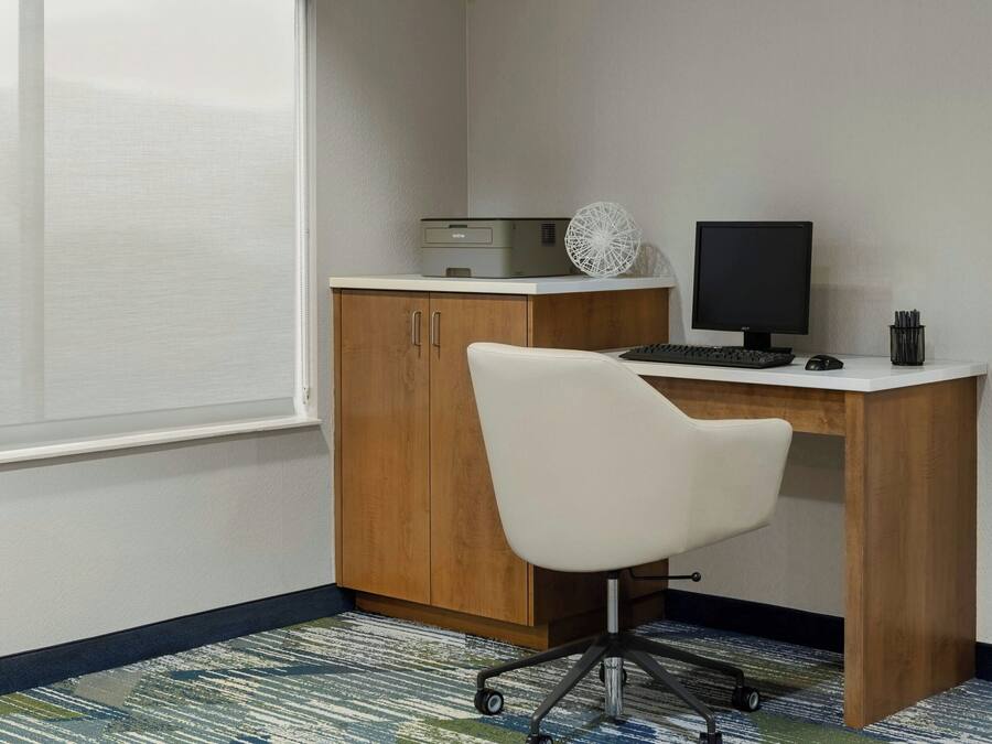 A small office space with a desk, chair, computer monitor, keyboard, and printer.