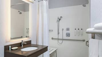 A modern bathroom with a sink, mirror, shower, and towel rack.