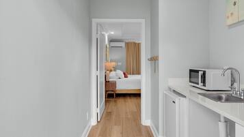 Habitación de hotel compacta con kitchenette, una cama y un baño visible a través de una puerta abierta.