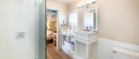 Een moderne badkamer met een douchecabine van glas, een wastafel met twee kommen en een toilet.