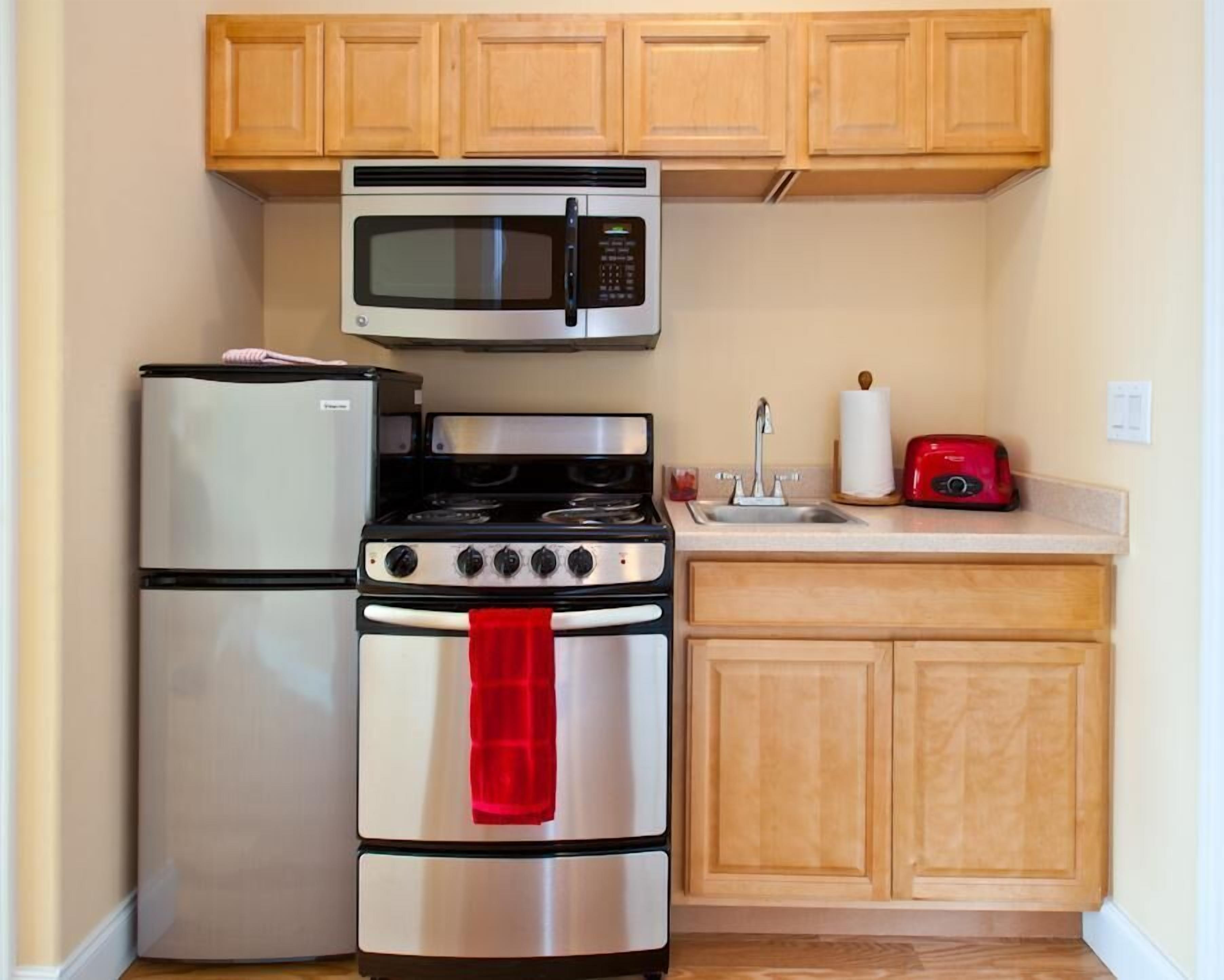 A compact kitchen with a refrigerator, microwave, stove, and sink.