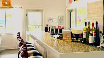 Une cuisine moderne avec un coin bar, des tabourets de bar et des bouteilles de vin.