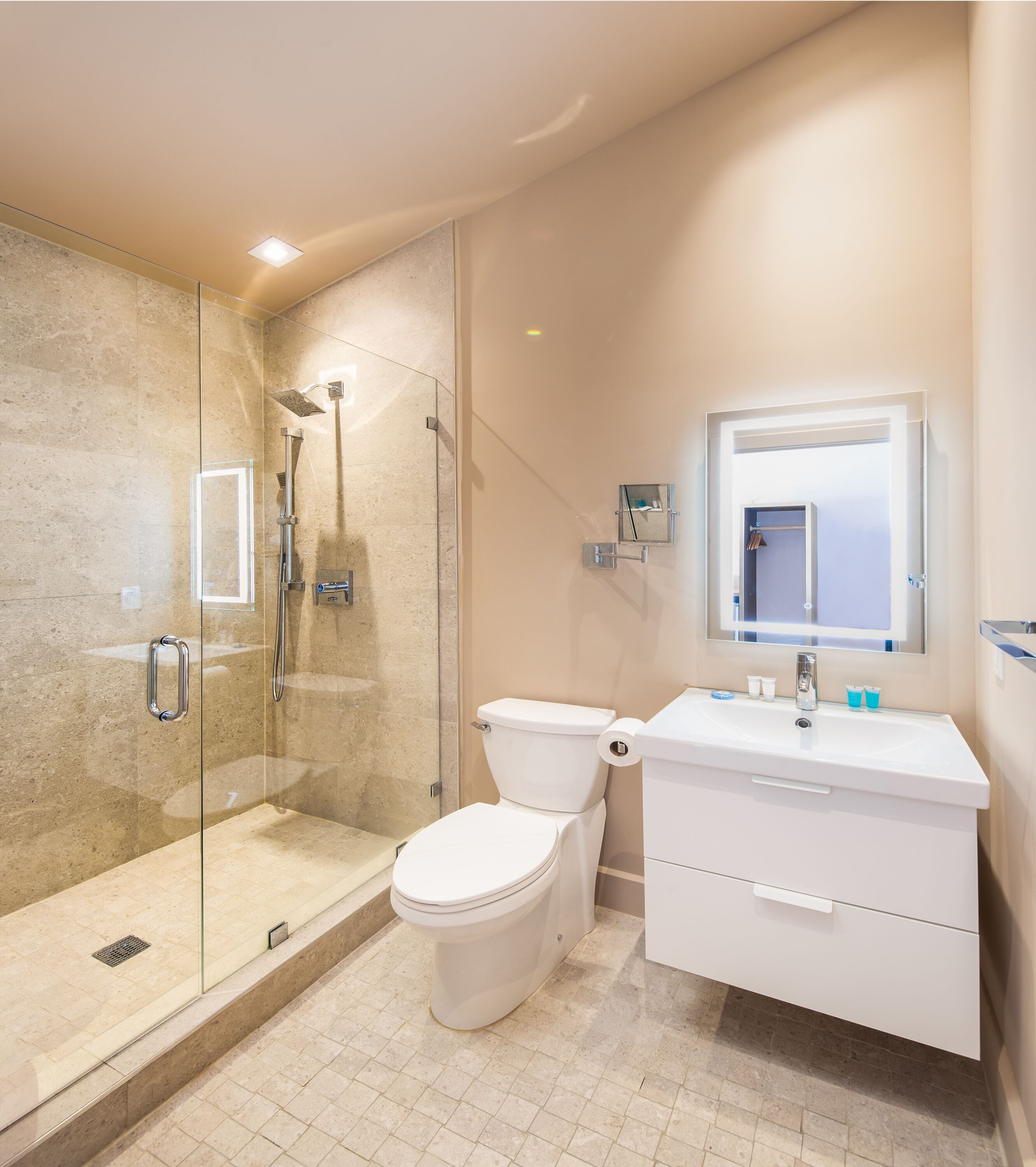 A modern bathroom with a glass-enclosed shower, a toilet, and a vanity with a mirror.