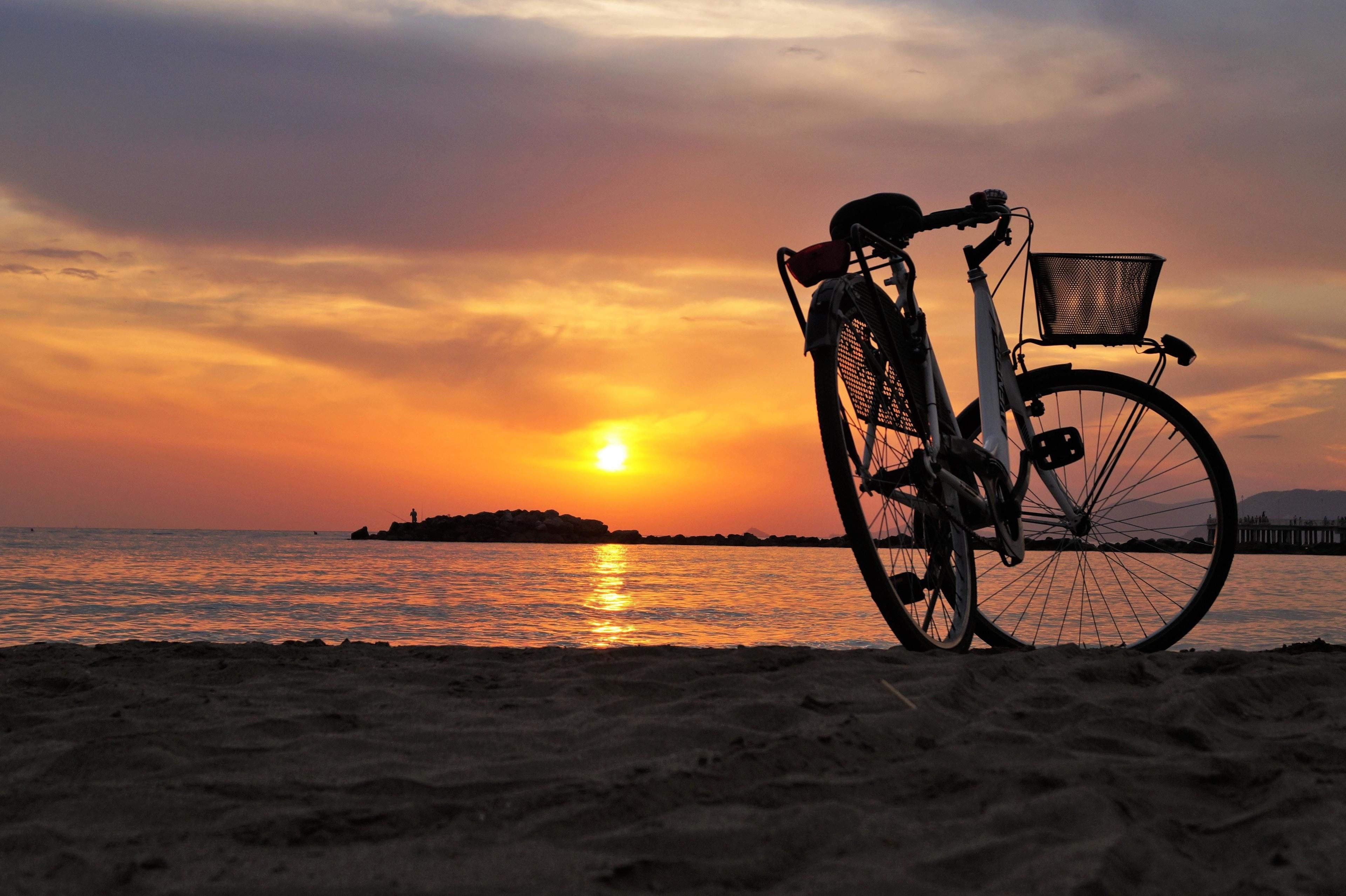 Una bicicleta con una cesta en la playa al atardecer.