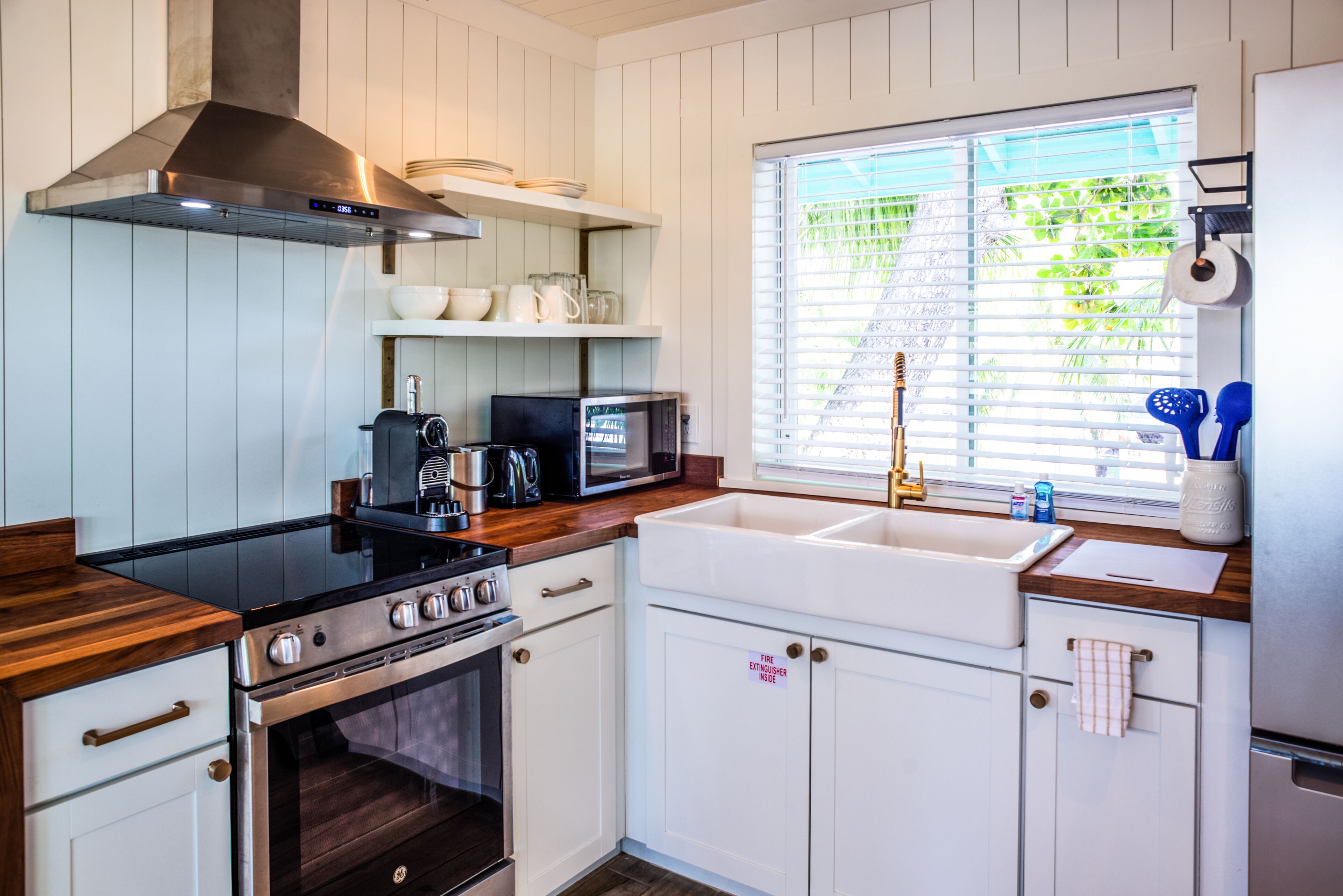 A kitchen with white cabinets, a stainless steel stove, a microwave, and a sink.