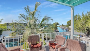 A covered outdoor area with wicker furniture and a view of a pool and boats.