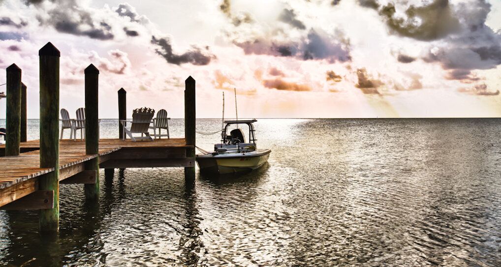 A wooden pier extending into calm waters with a boat docked at the end.