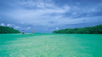 A calm sea with two people fishing on a small boat.