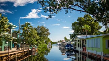 Um canal com barcos, rodeado por vegetação exuberante e edifícios com estilo arquitetônico tropical.