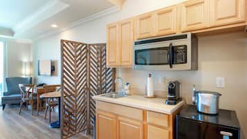 A compact kitchen with wooden cabinets, a built-in microwave, a coffee maker, and a kettle.
