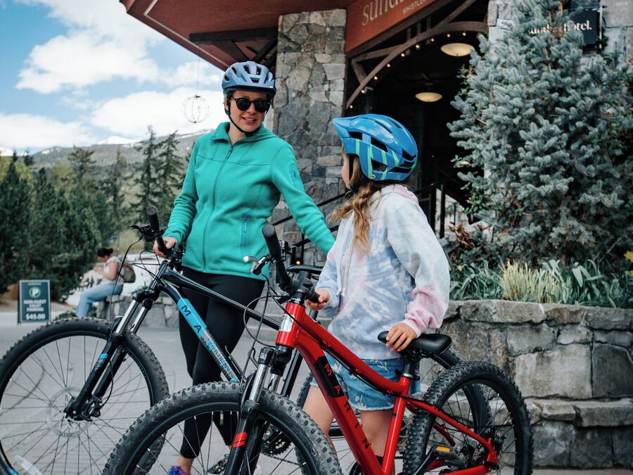 Dos personas con bicicletas frente a un edificio que dice 'sundial hotel'.