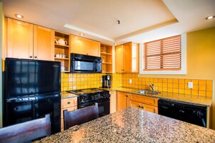 Una cocina con armarios de madera, un refrigerador negro, un microondas, una estufa y un lavavajillas.