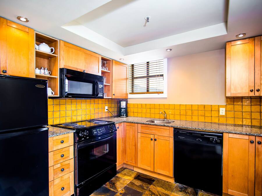 A kitchen with wooden cabinets, a black refrigerator, a microwave, a stove, and a dishwasher.