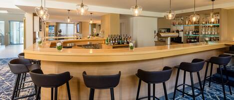A bar area with a curved counter, bar stools, and hanging pendant lights.