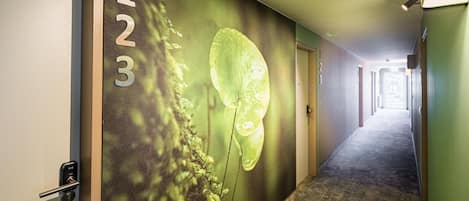 A hotel hallway with a number sign on the wall, a textured wall design, and a carpeted floor.