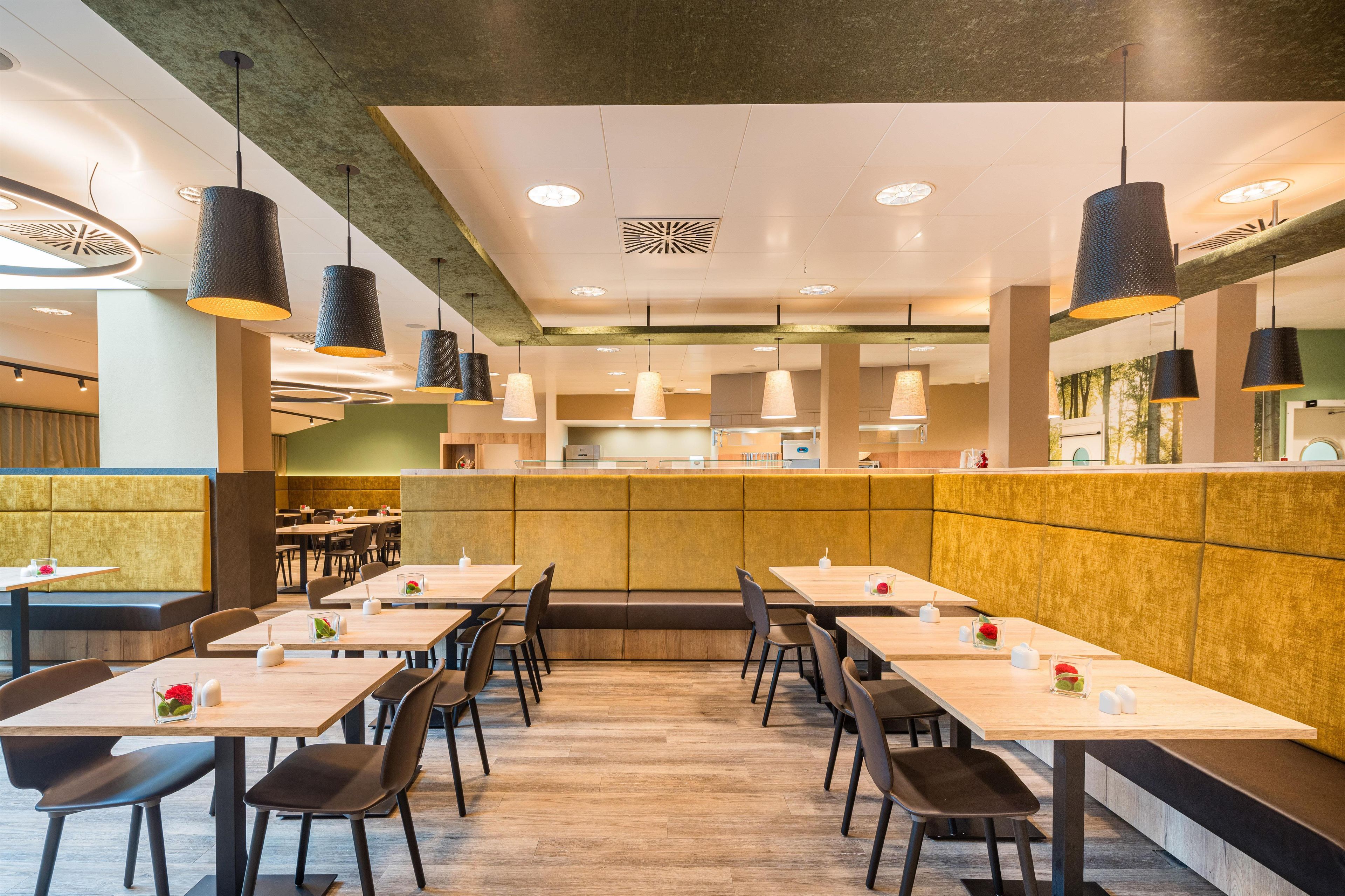Un interior de restaurante con mesas altas, cabinas y lámparas colgantes.