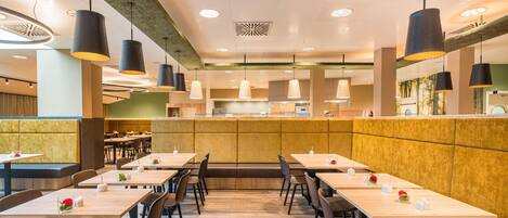 A restaurant interior with high tables, booths, and hanging pendant lights.