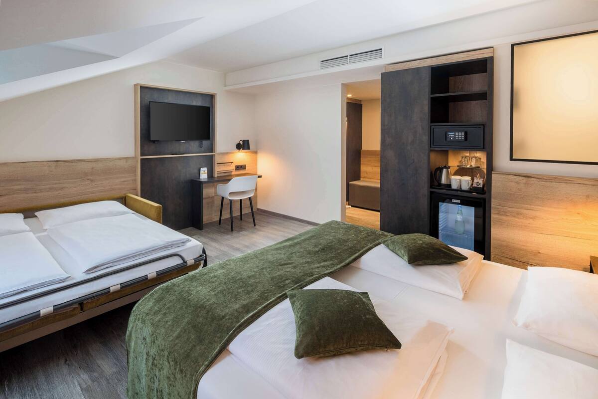 Een hotelkamer met twee bedden, een bureau, een televisie en een minibar.