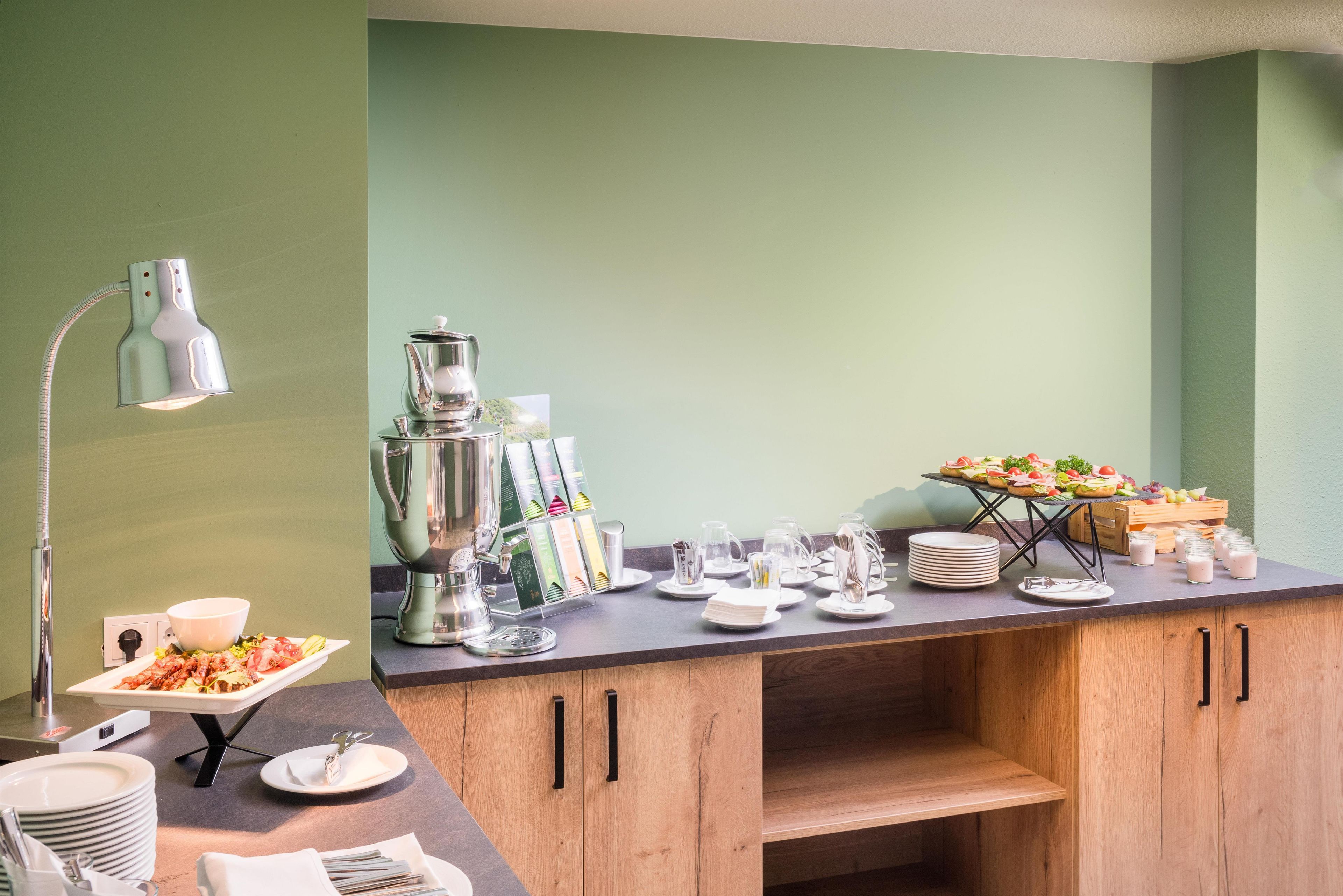 A breakfast bar with a coffee machine, tea kettle, and a variety of food and drink options.