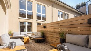 An outdoor patio with a wooden deck, a sofa, a table, and potted plants. - Best Western Hotel Muenchen Airport (Erding)