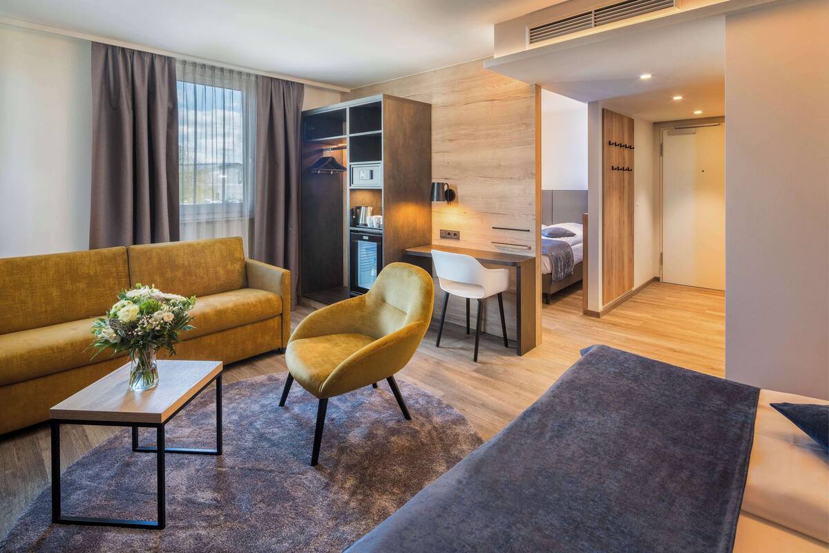Een moderne woonkamer met een bank, fauteuil, salontafel, een klein bureau en een kledingkast.