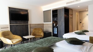 A hotel room with two beds, a TV, a wardrobe, and a seating area with chairs. - Best Western Hotel Muenchen Airport (Erding)