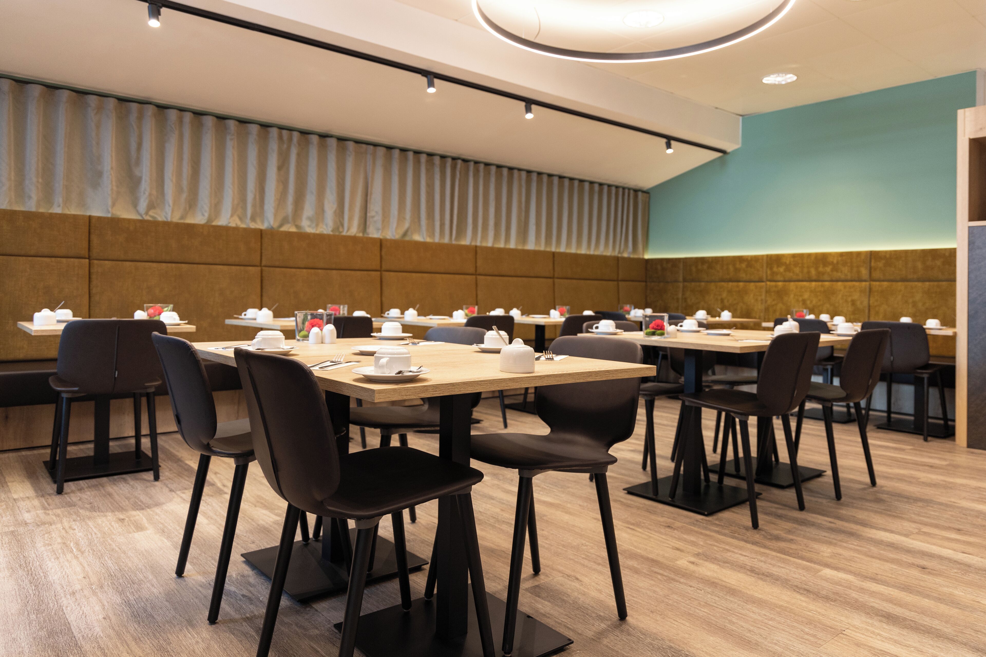 Ein Konferenzraum mit mehreren Tischen und Stühlen, ausgestattet mit Namensschildern und gedeckten Plätzen.