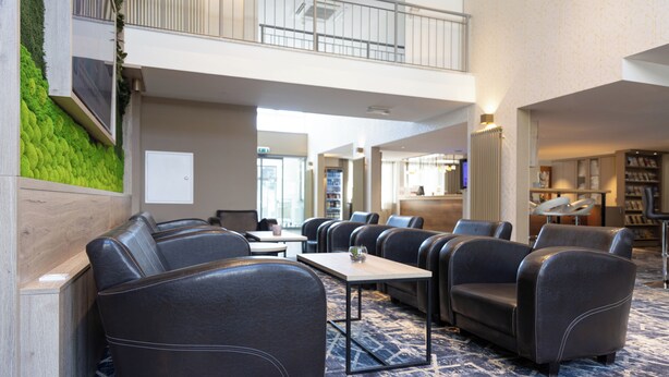 A hotel lobby with leather seating, a coffee table, and a patterned carpet. - Best Western Hotel Muenchen Airport (Erding)