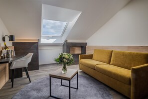 Un appartement moderne de style « loft », doté d’une verrière, d’un canapé, d’une table à manger avec des chaises et d’un vase rempli de fleurs.
