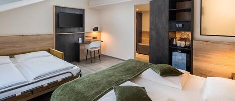 A hotel room with two beds, a desk, a television, and a minibar.