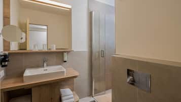 Un baño moderno con lavamanos, espejo, toallero y zona de ducha.