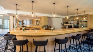 A bar area with a curved counter, black bar stools, and hanging pendant lights. - Best Western Hotel Muenchen Airport (Erding)