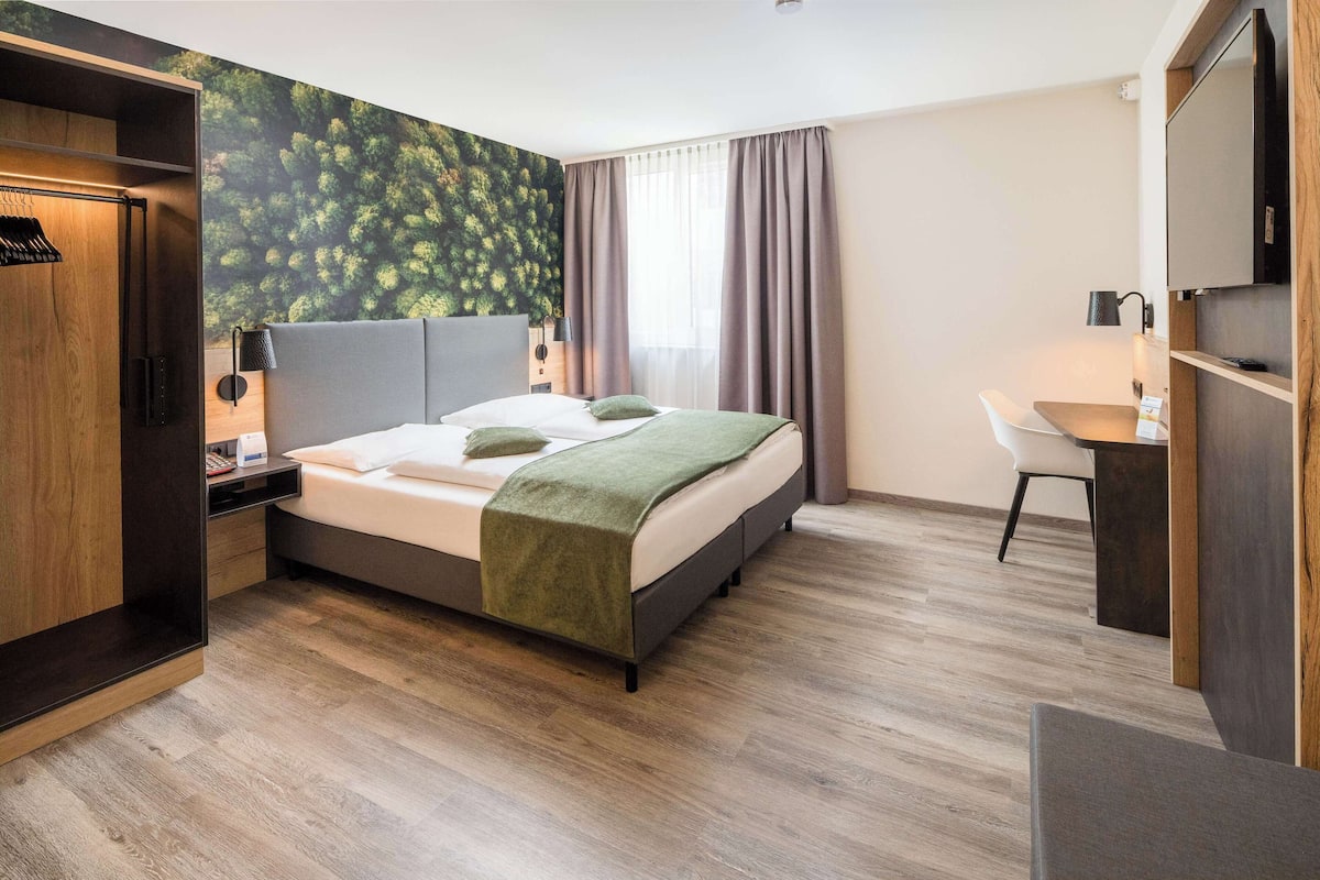 Een moderne hotelkamer met een bed, een bureau en een kledingkast.