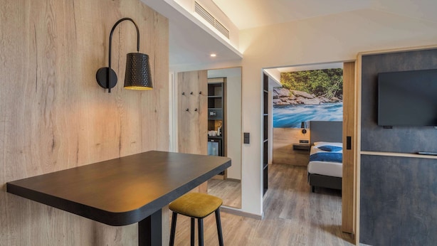 A modern interior with a bar area, a TV mounted on the wall, and a view of a river through an open doorway. - Best Western Hotel Muenchen Airport (Erding)